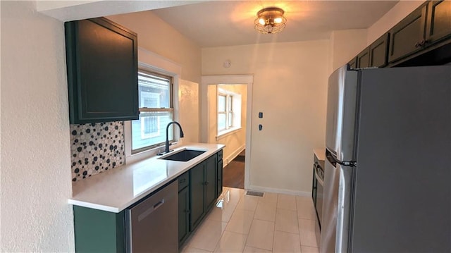 kitchen with stainless steel appliances, tasteful backsplash, light countertops, a sink, and baseboards