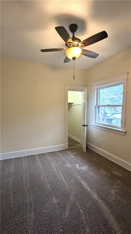 unfurnished bedroom featuring ceiling fan, dark carpet, and baseboards