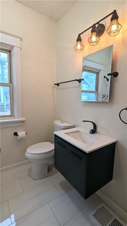 bathroom with visible vents, toilet, vanity, a textured ceiling, and baseboards