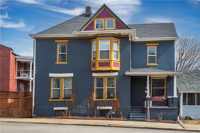 319 Park Ave, Kansas City, MO 64124 - view of front of home with covered porch, a chimney, fence, and roof with shingles
