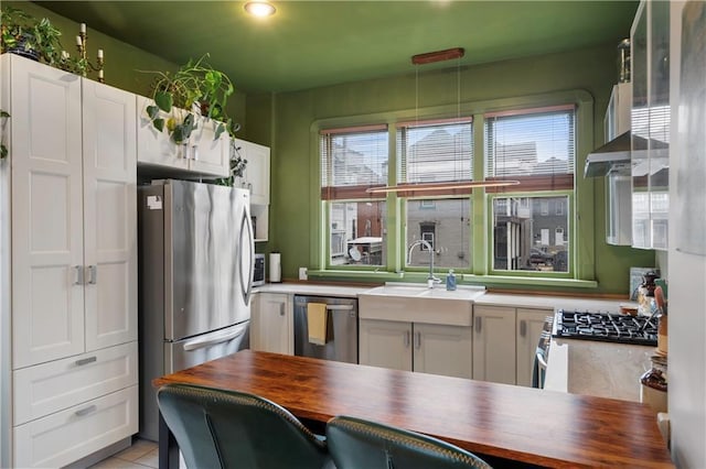 kitchen featuring stainless steel appliances, butcher block counters, and white cabinets