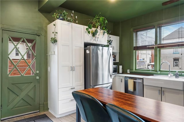 kitchen featuring appliances with stainless steel finishes, butcher block countertops, a sink, and white cabinetry