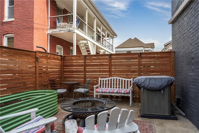 view of patio / terrace with cooling unit, fence, and a balcony