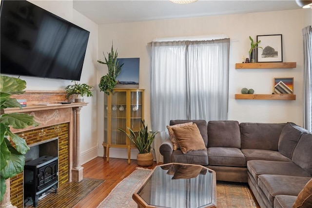 living area featuring wood finished floors, a wood stove, and baseboards