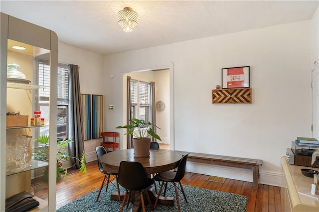 dining space featuring wood-type flooring and baseboards