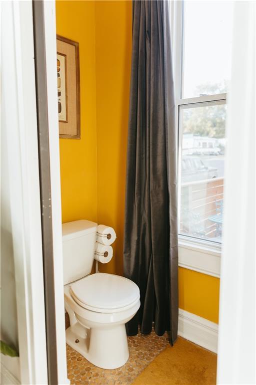 bathroom featuring toilet, a wealth of natural light, and baseboards