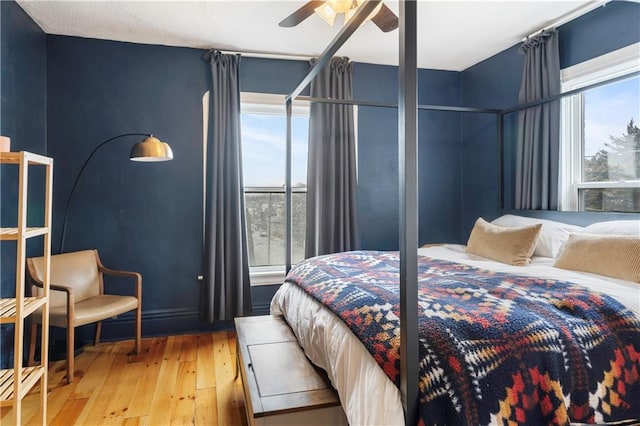 bedroom featuring a ceiling fan, multiple windows, and hardwood / wood-style floors