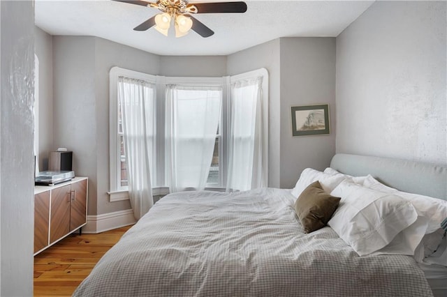 bedroom featuring light wood-type flooring, a ceiling fan, and baseboards