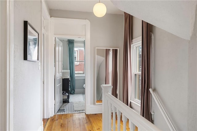 hallway with an upstairs landing and light wood-style floors