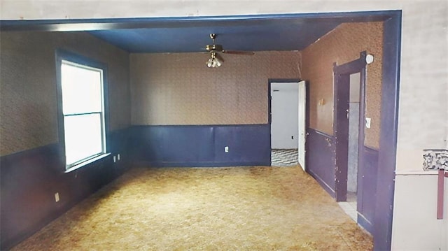 unfurnished room with wainscoting and wallpapered walls