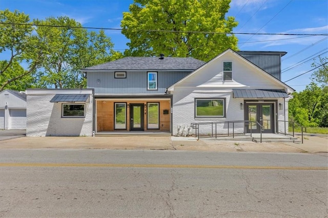 view of front of house featuring brick siding, french doors, and fence