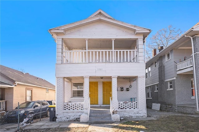 view of front of property featuring brick siding, covered porch, and a balcony