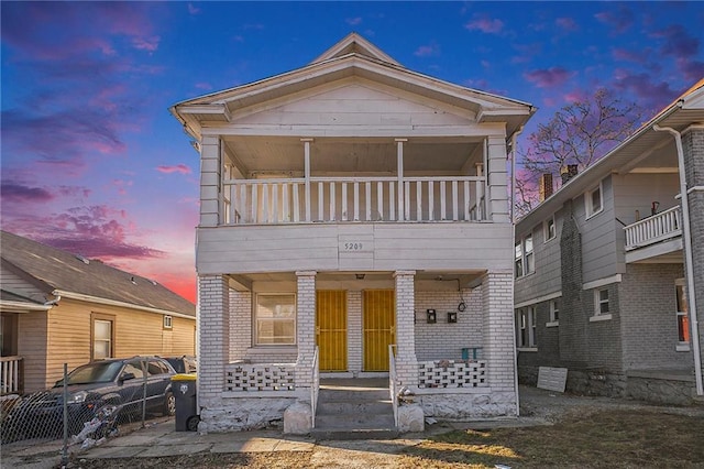 view of front facade with brick siding, covered porch, and a balcony