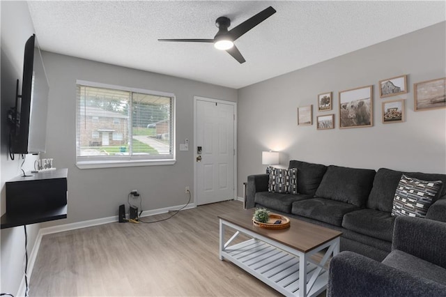 living area with a ceiling fan, light wood-style floors, baseboards, and a textured ceiling