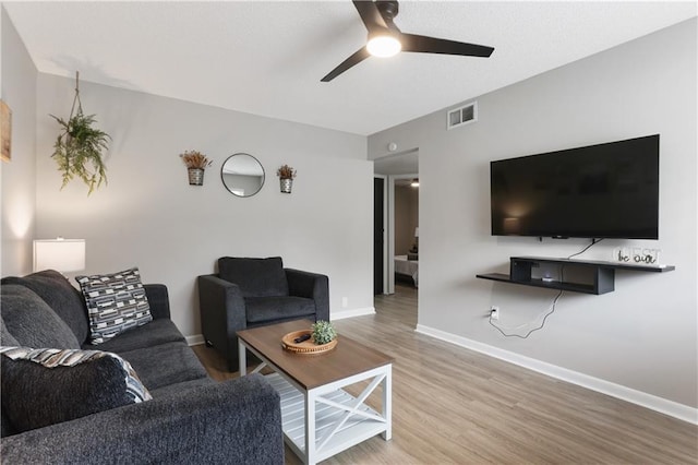 living room with visible vents, a ceiling fan, baseboards, and wood finished floors