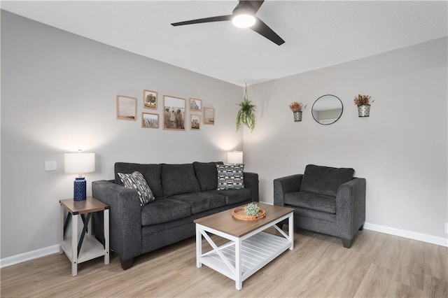 living area with a ceiling fan, baseboards, and light wood finished floors