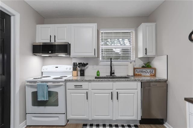 kitchen with a sink, stainless steel microwave, tasteful backsplash, white range with electric stovetop, and white cabinets