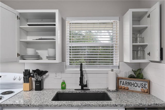 kitchen with a sink, light stone counters, decorative backsplash, white range with electric stovetop, and open shelves