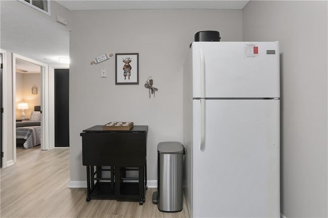 kitchen with visible vents, baseboards, wood finished floors, and freestanding refrigerator