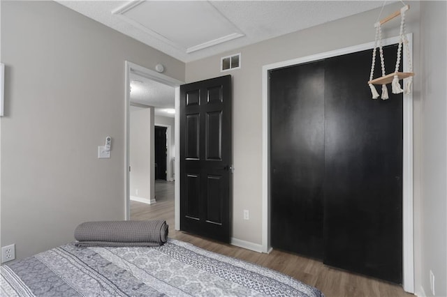 unfurnished bedroom featuring visible vents, a textured ceiling, wood finished floors, a closet, and baseboards