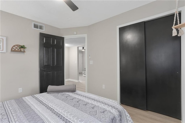 bedroom with ceiling fan, visible vents, a closet, and light wood-style flooring