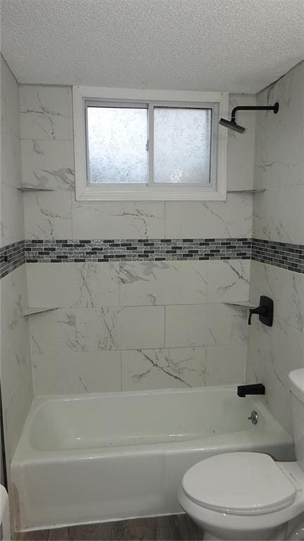 bathroom with a textured ceiling, toilet, and shower / tub combination