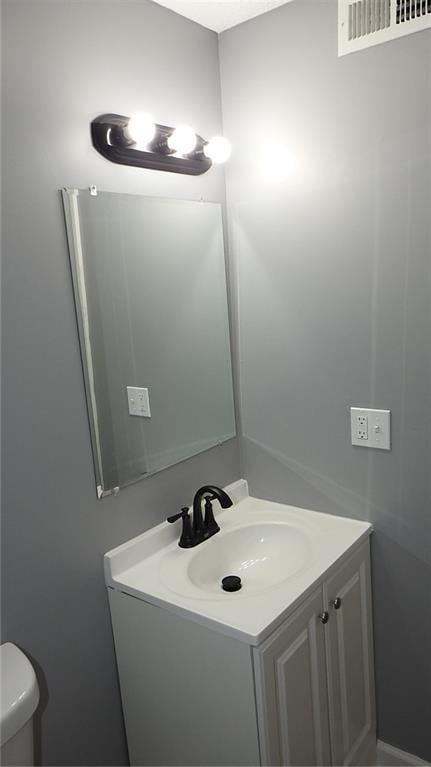 bathroom with visible vents, toilet, and vanity