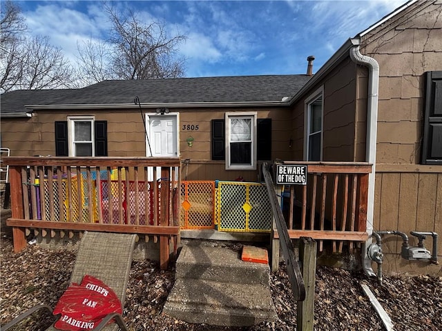 exterior space featuring a shingled roof and a wooden deck