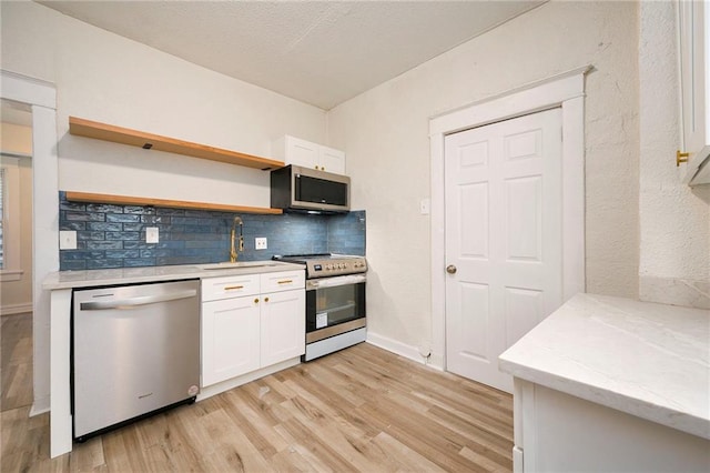 kitchen with light wood finished floors, tasteful backsplash, white cabinetry, and stainless steel appliances