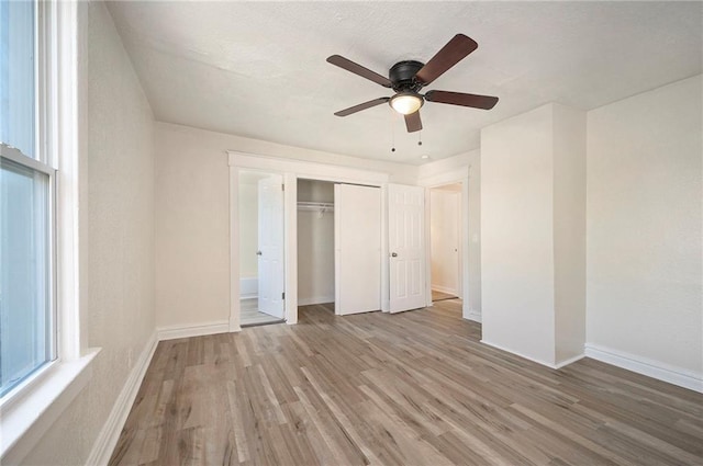 unfurnished bedroom featuring ceiling fan, a closet, light wood-style flooring, and baseboards