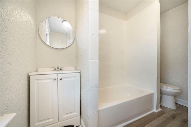 bathroom featuring a textured wall, vanity, wood finished floors, and toilet