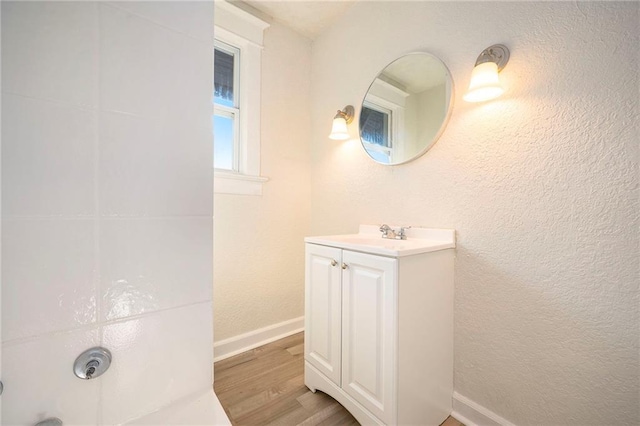 bathroom featuring a textured wall, baseboards, wood finished floors, and vanity