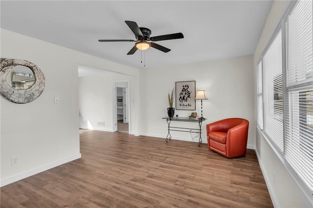 sitting room with a ceiling fan, baseboards, and wood finished floors