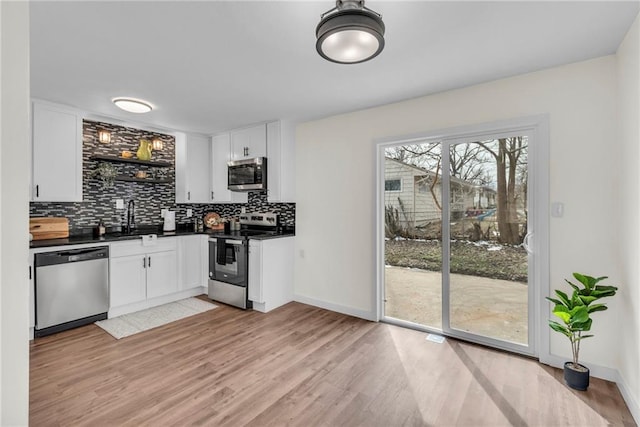 kitchen featuring dark countertops, white cabinetry, tasteful backsplash, and appliances with stainless steel finishes