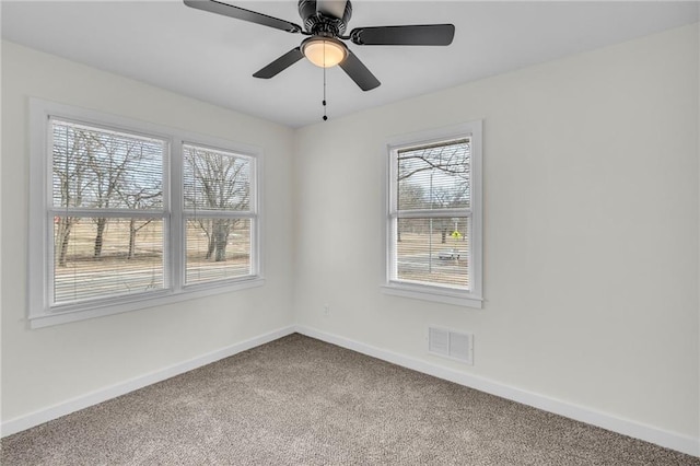 carpeted spare room with a ceiling fan, visible vents, and baseboards