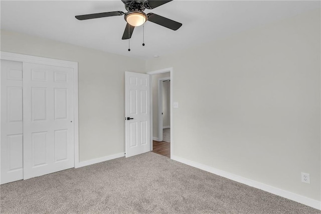 unfurnished bedroom featuring carpet, a closet, baseboards, and a ceiling fan