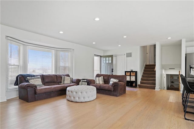 living area with recessed lighting, visible vents, baseboards, stairway, and light wood-type flooring