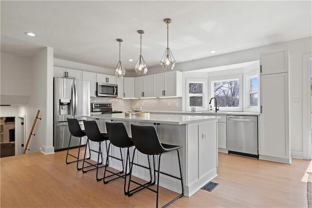 kitchen featuring light wood-style floors, a kitchen island, a breakfast bar area, and stainless steel appliances