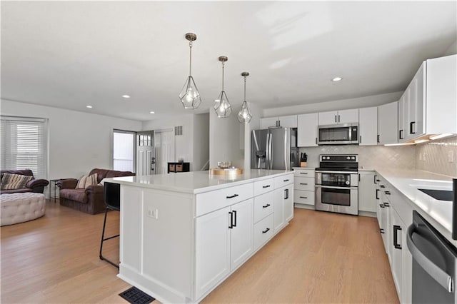 kitchen featuring open floor plan, stainless steel appliances, visible vents, and light wood-style floors