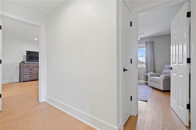 hallway featuring light wood-style flooring and baseboards