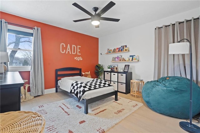 bedroom with a ceiling fan, baseboards, and wood finished floors