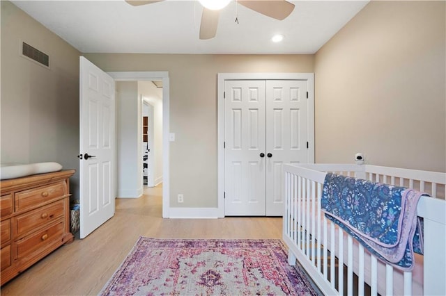 bedroom with light wood finished floors, a closet, visible vents, a ceiling fan, and baseboards