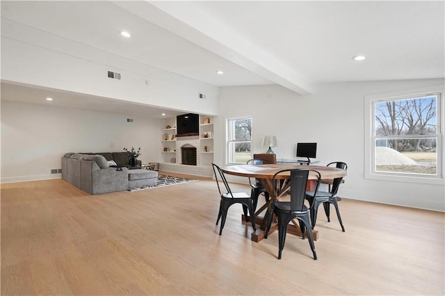 dining space featuring vaulted ceiling with beams, recessed lighting, visible vents, a brick fireplace, and light wood finished floors