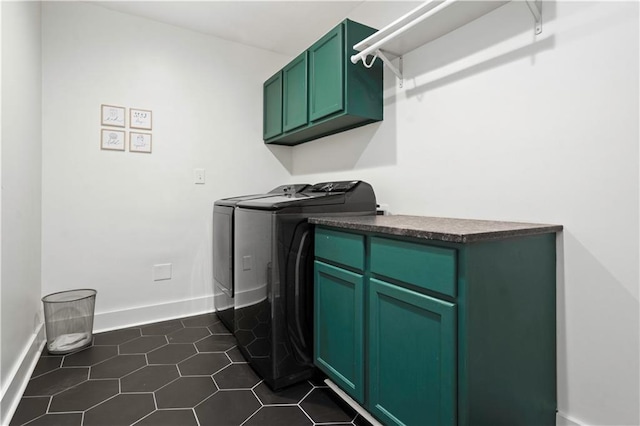 laundry area featuring cabinet space, dark tile patterned floors, baseboards, and washer and dryer