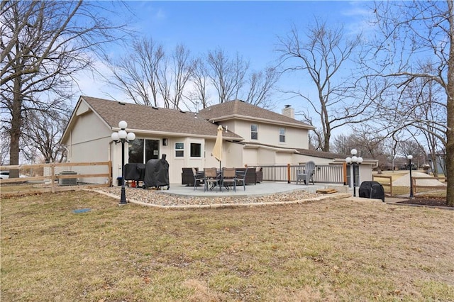 back of property with a lawn, fence, a chimney, and a patio