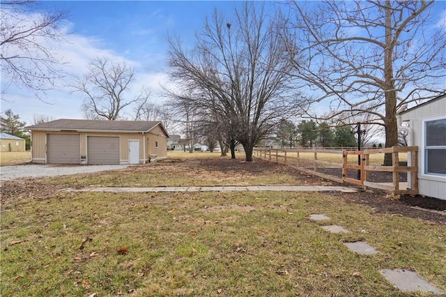 view of yard featuring a garage, an outbuilding, and fence