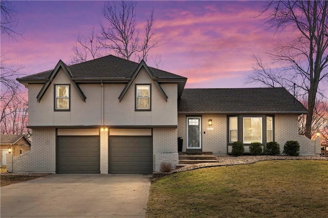 view of front of house featuring a lawn, concrete driveway, roof with shingles, an attached garage, and brick siding