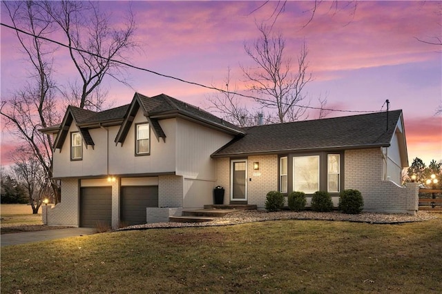 split level home featuring a garage, driveway, brick siding, and a front yard