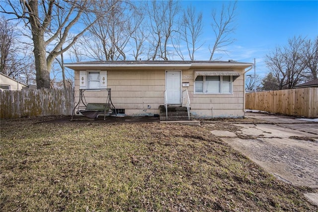 view of front of house with entry steps, fence, and a front yard