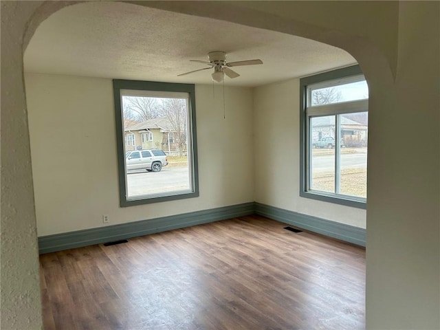 unfurnished room featuring plenty of natural light, visible vents, and arched walkways